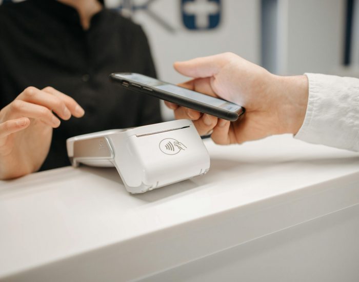 Person using a smartphone for contactless payment at a retail counter, highlighting cashless convenience.